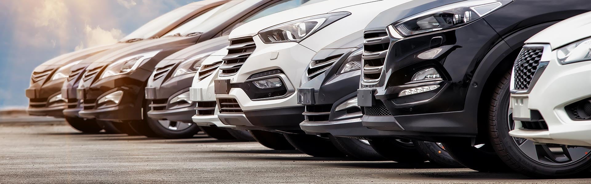 Row of cars and SUVs parked at a dealership lot.
